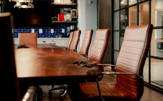 A conference room with a large wooden table and leather chairs